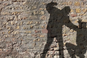 Shadow of a person appearing to threaten another, cast on a brick wall.